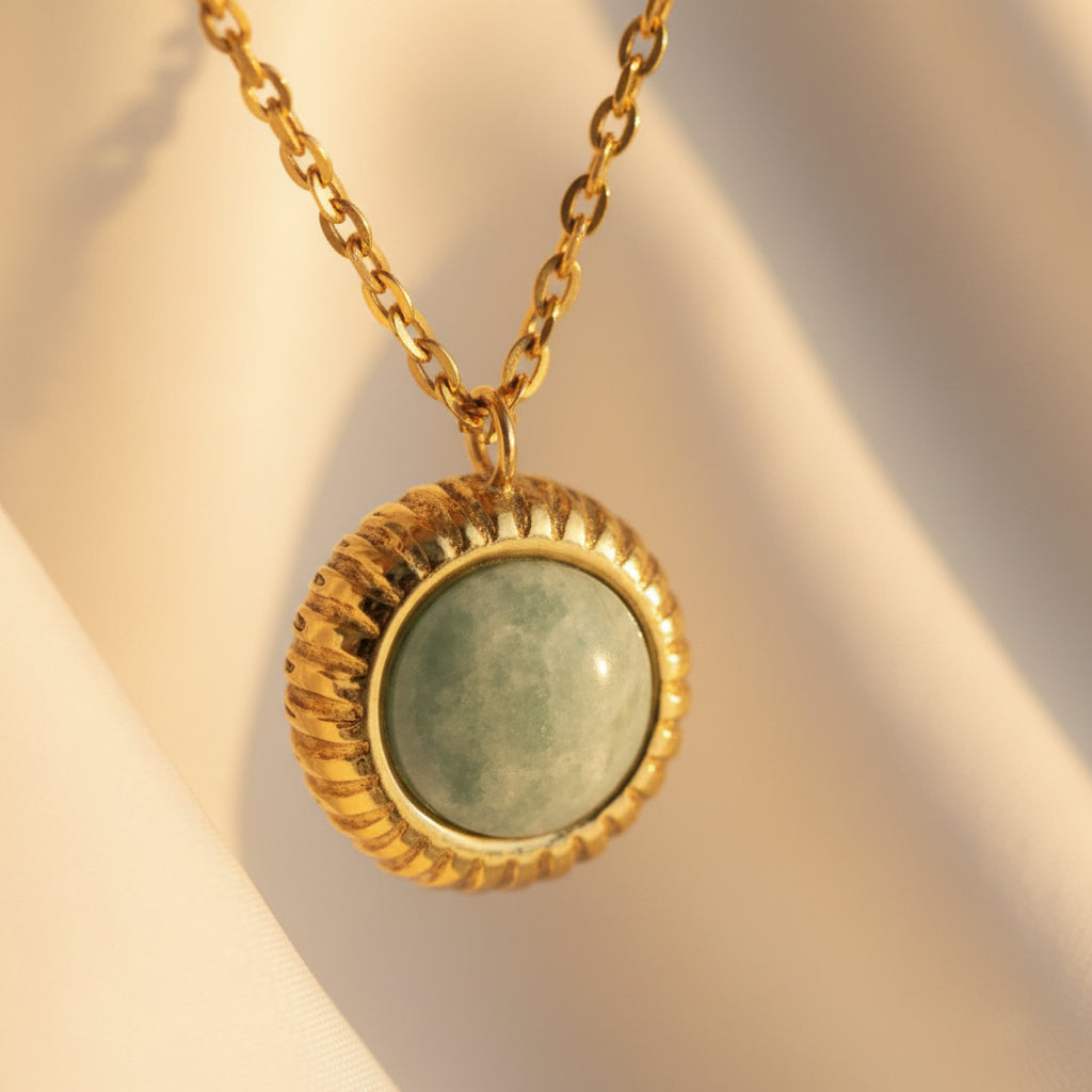 Layered gold necklace with snake chain and sage green pendant on a #5b3b3a luxury catalogue background.