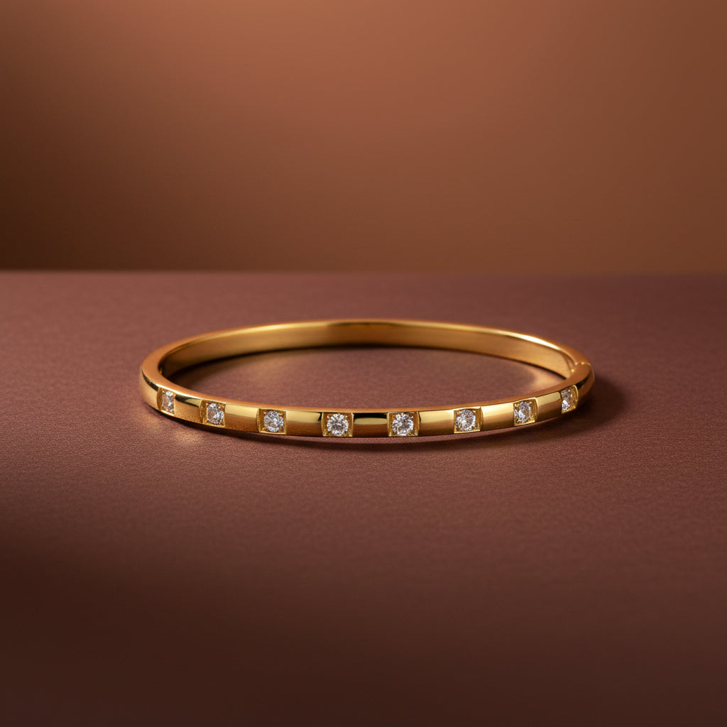 A professional high-angle catalogue shot of the gold plated block-station crystal oval kada bangle, sized specifically for thin wrists, isolated on a deep cocoa brown background with simple shadows, as seen in WhatsApp Image 2026-06-18 at 9.29.03 AM.jpeg.
