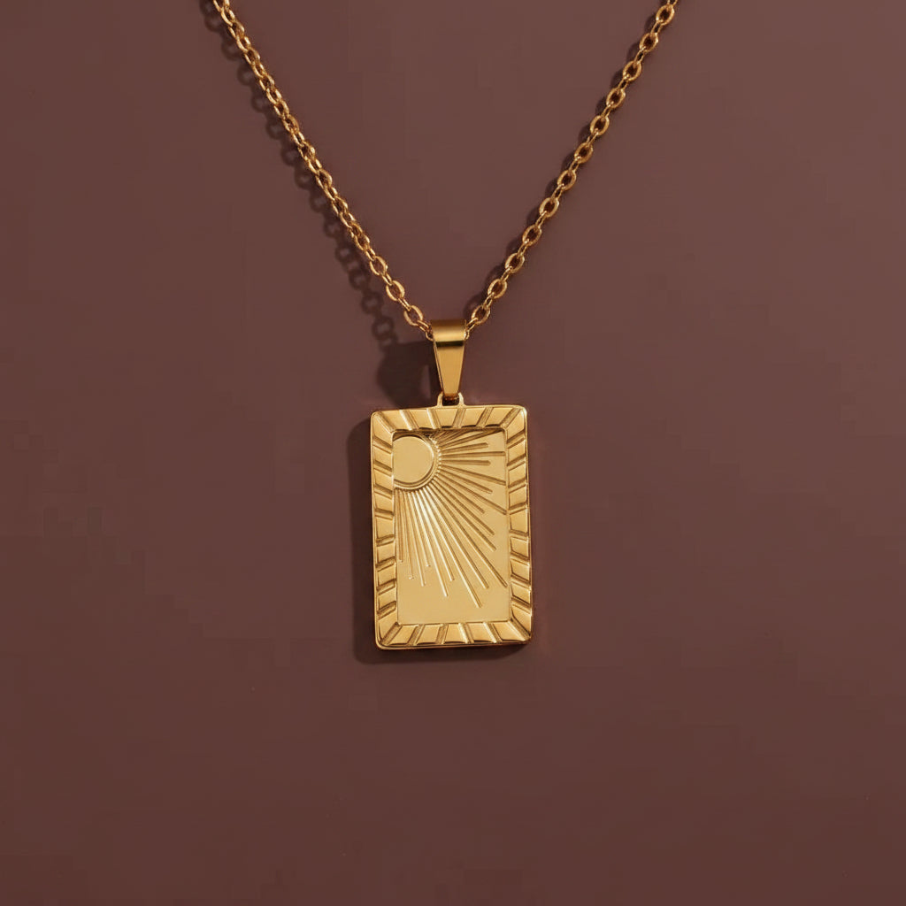 A professional catalogue flat-lay image showing the 18K gold rectangular sun talisman necklace arranged in a precise circle with clean shadows on a plain cocoa brown background.