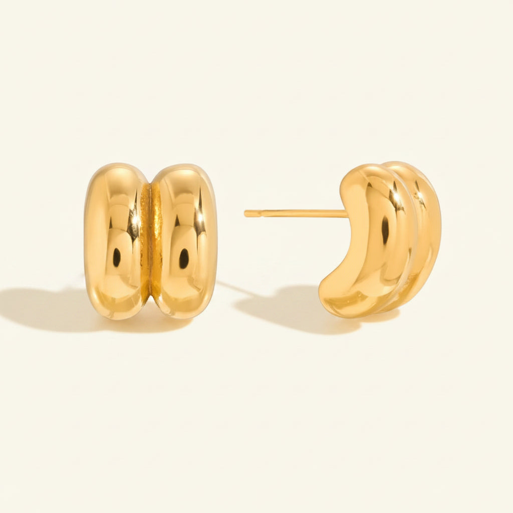 Professional standing catalogue shot of the high-polish liquid gold double dome studs with simple shadows on a light cream background.